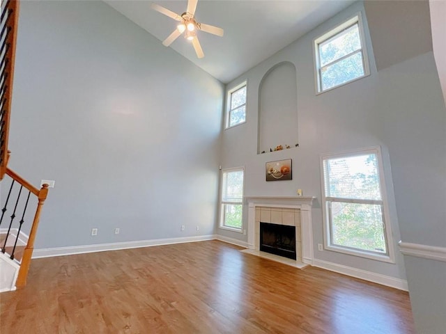 unfurnished living room featuring high vaulted ceiling, ceiling fan, a wealth of natural light, and light hardwood / wood-style flooring