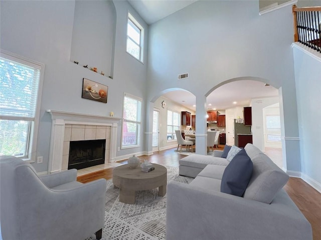 living room with a tile fireplace, a high ceiling, and light hardwood / wood-style flooring