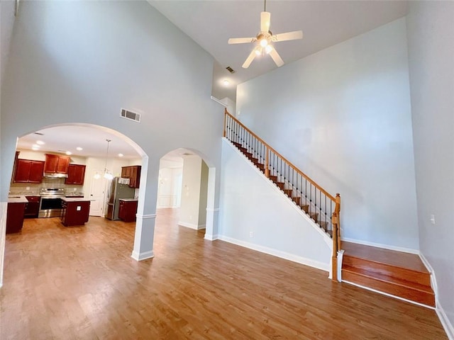 living room with ceiling fan, wood-type flooring, and a high ceiling