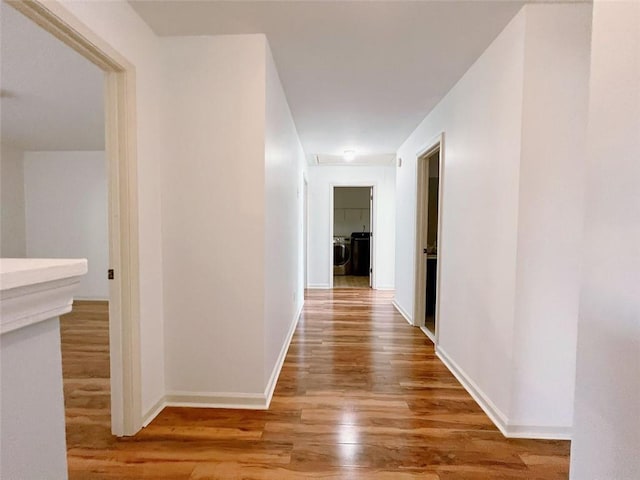 hallway with wood-type flooring and washing machine and dryer