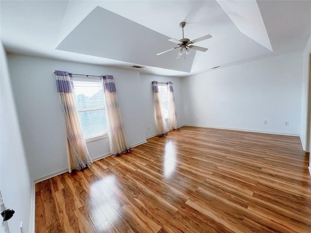 unfurnished room featuring light hardwood / wood-style floors, ceiling fan, and a tray ceiling