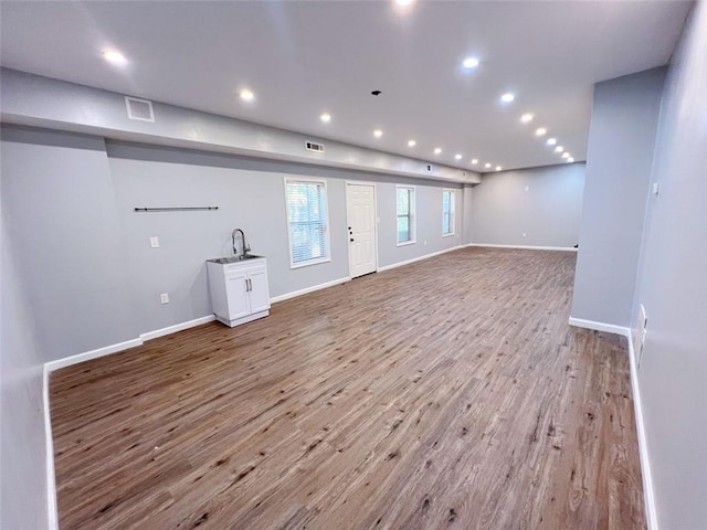 unfurnished living room featuring sink and light hardwood / wood-style floors