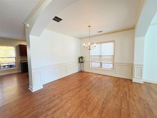 unfurnished dining area with a chandelier, hardwood / wood-style floors, and ornamental molding