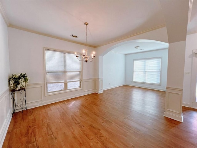 unfurnished dining area with a chandelier, wood-type flooring, and ornamental molding