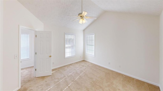 spare room featuring ceiling fan, light colored carpet, a healthy amount of sunlight, and vaulted ceiling