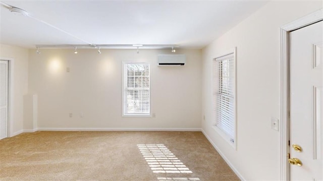 unfurnished room featuring rail lighting, an AC wall unit, and light carpet