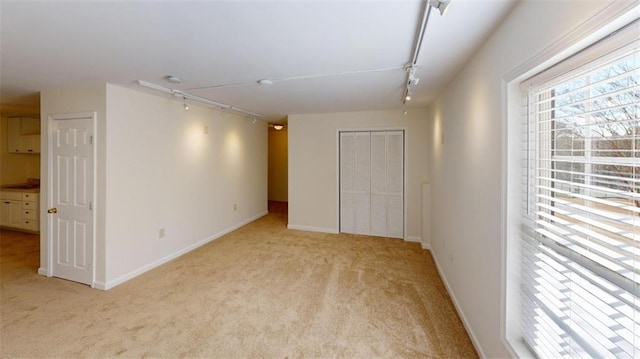 unfurnished room featuring light carpet and track lighting