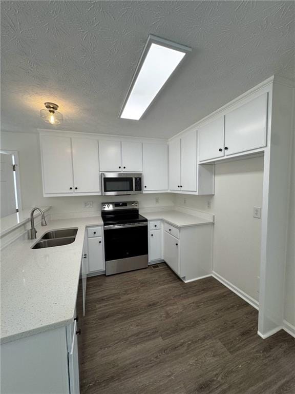 kitchen featuring sink, appliances with stainless steel finishes, light stone countertops, white cabinets, and dark hardwood / wood-style flooring