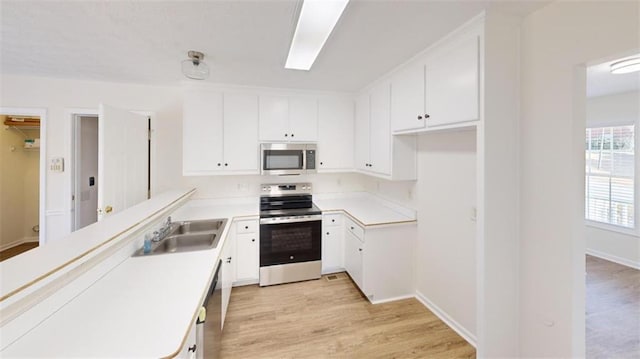 kitchen with white cabinetry, sink, light wood-type flooring, and appliances with stainless steel finishes