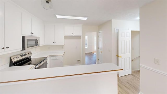 kitchen featuring stainless steel appliances, kitchen peninsula, light wood-type flooring, and white cabinets