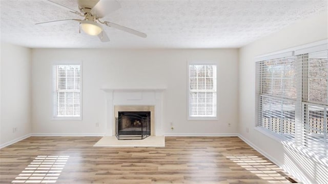 unfurnished living room featuring ceiling fan, a textured ceiling, and light hardwood / wood-style flooring