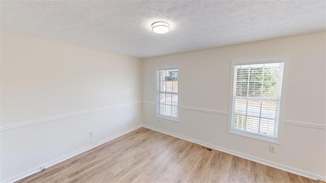 empty room with a textured ceiling and light wood-type flooring