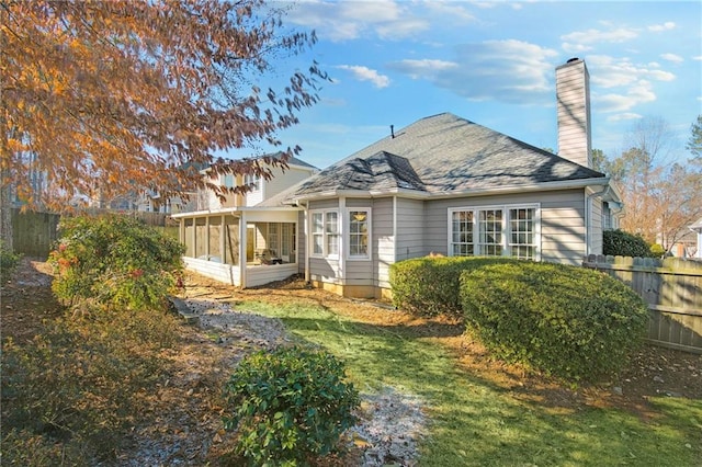 back of property featuring a sunroom and a yard