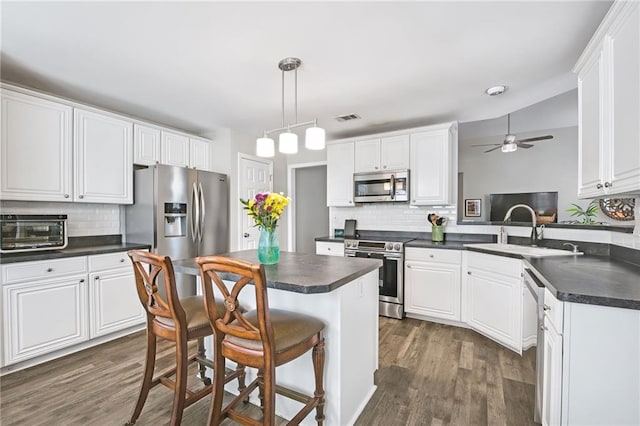 kitchen featuring a breakfast bar area, kitchen peninsula, white cabinets, and appliances with stainless steel finishes