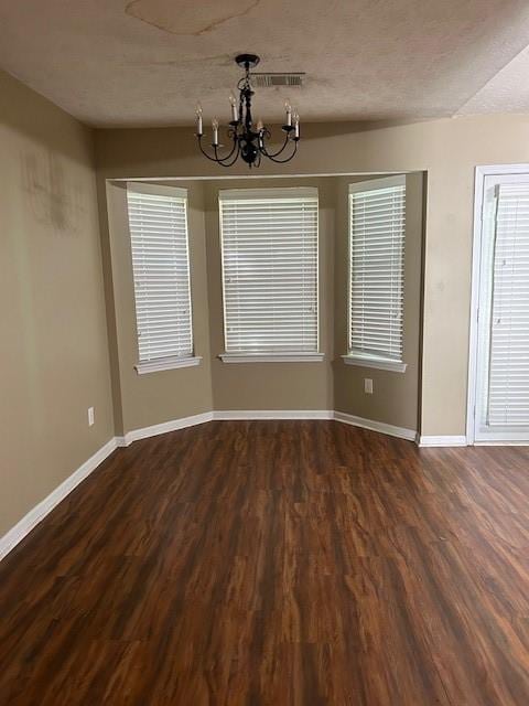 unfurnished dining area featuring a chandelier and dark hardwood / wood-style floors