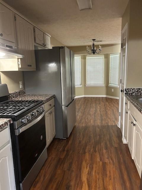 kitchen with a notable chandelier, dark hardwood / wood-style flooring, stainless steel gas range oven, and white cabinets