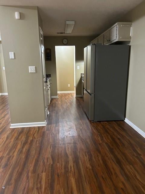 kitchen with dark wood-type flooring, stainless steel fridge, and white cabinetry