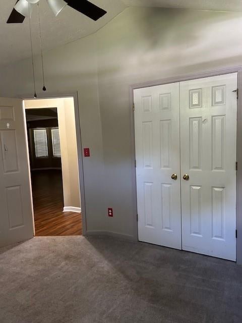 unfurnished bedroom with lofted ceiling, dark colored carpet, ceiling fan, and a closet