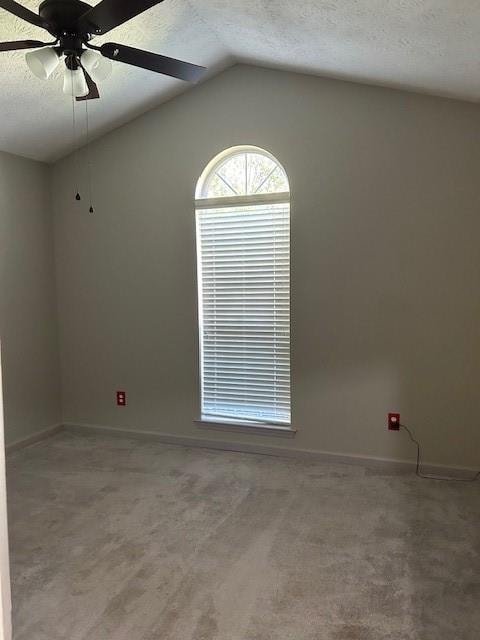 empty room with lofted ceiling, ceiling fan, carpet floors, and a textured ceiling