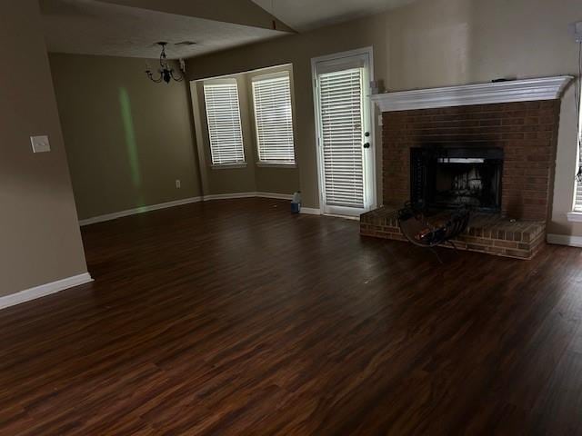 unfurnished living room with plenty of natural light, vaulted ceiling, dark hardwood / wood-style floors, and a fireplace