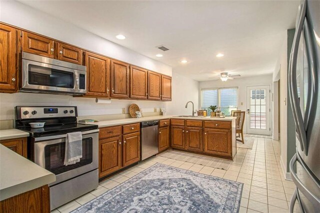 1484 Winston Pl, Decatur, GA 30033 - kitchen with a peninsula, a sink, visible vents, brown cabinets, and appliances with stainless steel finishes