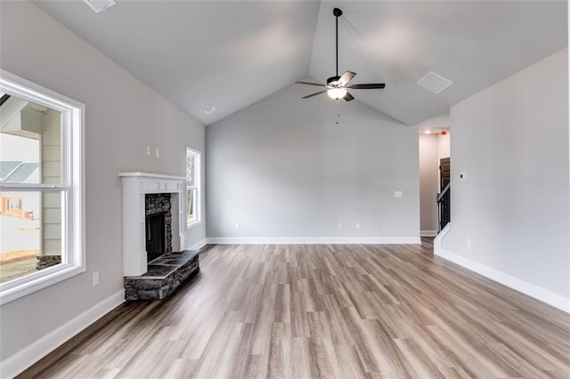 unfurnished living room featuring a premium fireplace, ceiling fan, lofted ceiling, and light wood-type flooring