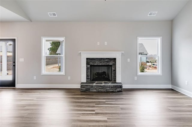 unfurnished living room with a stone fireplace, lofted ceiling, and hardwood / wood-style flooring