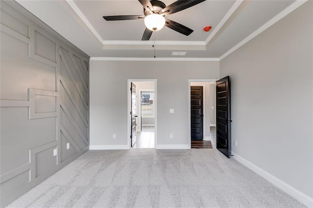 carpeted empty room featuring a tray ceiling, ceiling fan, and ornamental molding