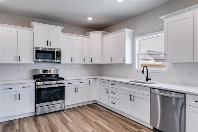 kitchen with sink, white cabinetry, stainless steel appliances, and tasteful backsplash