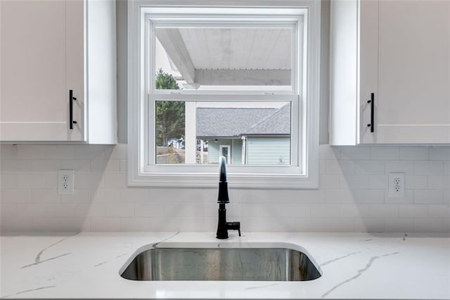 room details with light stone countertops, white cabinets, and sink