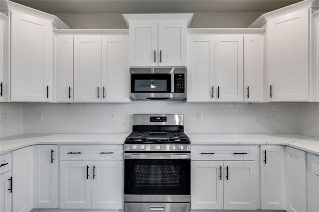 kitchen with backsplash, light stone countertops, white cabinets, and appliances with stainless steel finishes