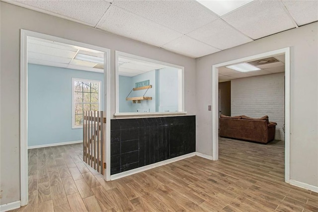 interior space with a paneled ceiling and light wood-type flooring