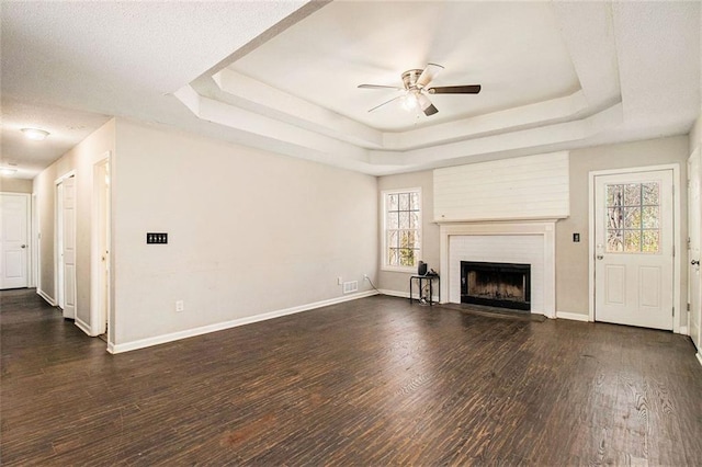 unfurnished living room with dark hardwood / wood-style floors, a large fireplace, and a raised ceiling