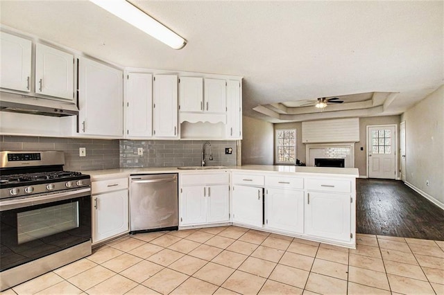 kitchen featuring appliances with stainless steel finishes, a tray ceiling, white cabinetry, and light tile patterned flooring