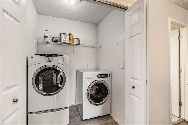 clothes washing area with washing machine and dryer and a textured ceiling