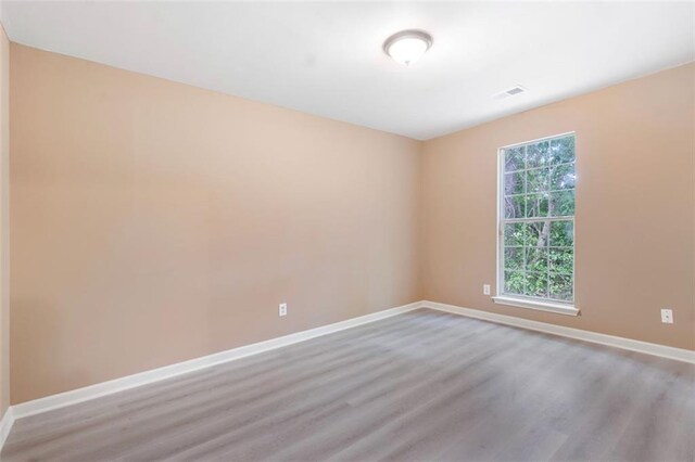 unfurnished room with baseboards, visible vents, and wood finished floors