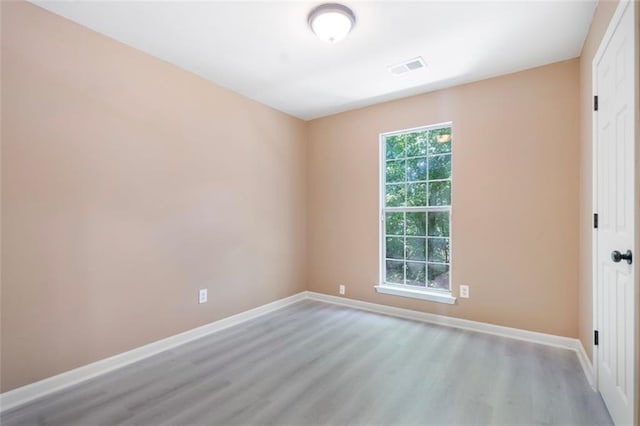empty room featuring baseboards, visible vents, and wood finished floors