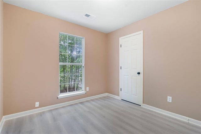unfurnished room with baseboards, light wood-type flooring, and visible vents
