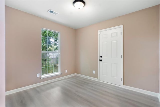 unfurnished room with baseboards, visible vents, and wood finished floors