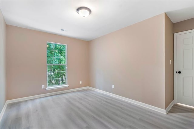 spare room with visible vents, light wood-style flooring, and baseboards
