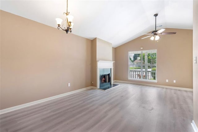 unfurnished living room featuring ceiling fan with notable chandelier, wood finished floors, vaulted ceiling, a lit fireplace, and baseboards