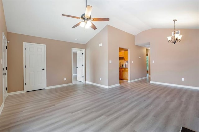 unfurnished living room featuring light wood-type flooring, vaulted ceiling, baseboards, and ceiling fan with notable chandelier