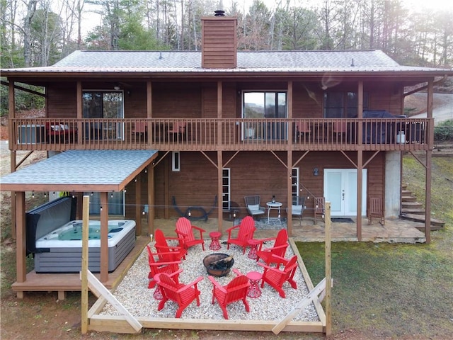 back of property featuring a deck, a hot tub, a patio, and an outdoor fire pit