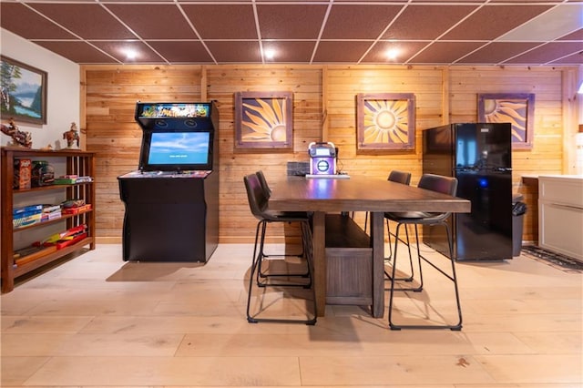 interior space with a paneled ceiling, wooden walls, and light hardwood / wood-style floors