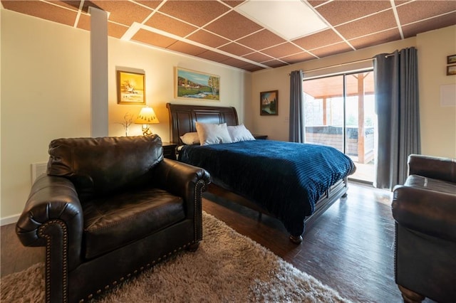 bedroom featuring access to outside, a drop ceiling, and dark hardwood / wood-style flooring