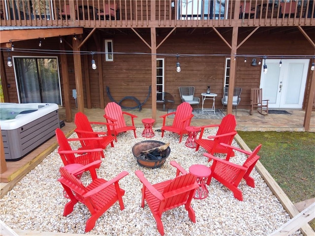 view of patio / terrace with a wooden deck, a hot tub, and a fire pit