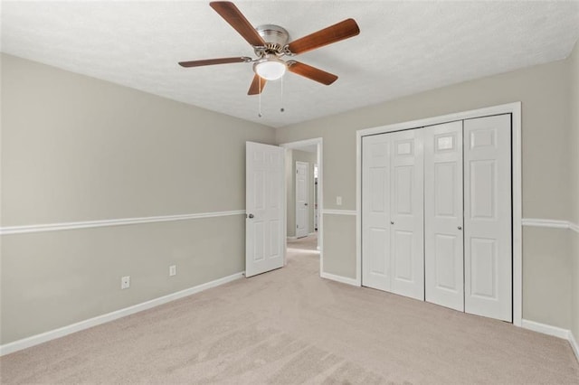 unfurnished bedroom featuring ceiling fan, light colored carpet, a closet, and a textured ceiling