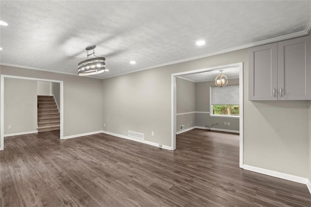 unfurnished room with an inviting chandelier, dark wood-type flooring, ornamental molding, and a textured ceiling