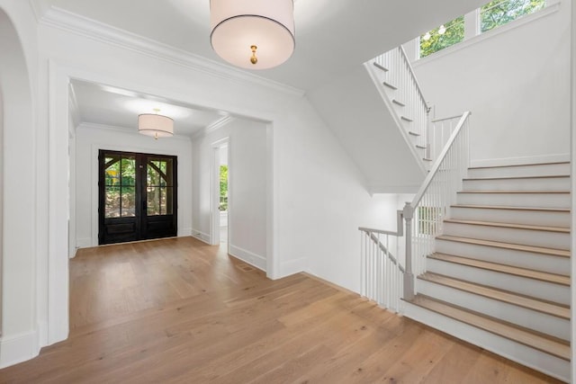 foyer featuring light wood-type flooring, french doors, and ornamental molding