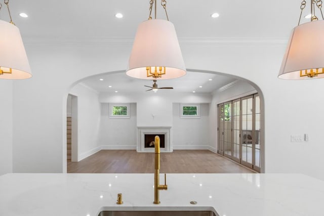 interior space featuring hanging light fixtures, ornamental molding, sink, ceiling fan, and light wood-type flooring